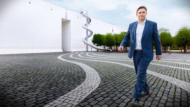 Man sieht Iliya vom Bundesministerium für wirtschaftliche Zusammenarbeit und Entwicklung auf einem Gebäudevorplatz laufen.