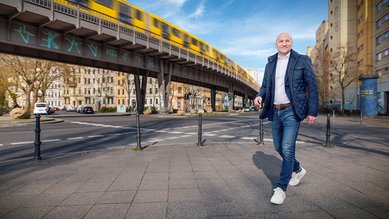 Man sieht Sebastian von der Digitalakademie Bund in Berlin laufen, im Hintergrund fährt eine Bahn.