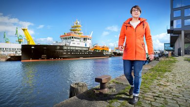 Man sieht Sina vom Bundesamt für Seeschifffahrt und Hydrographie vor einem Schiff im Hafen laufen.
